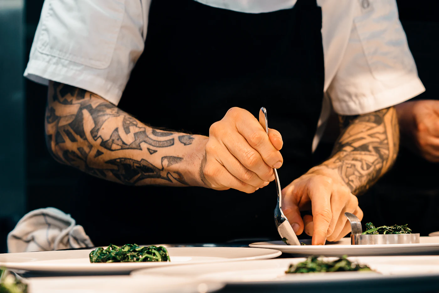Un cocinero termina un plato con pinzas